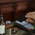 A close-up shot of a hand using a credit card with a swipe machine for payment.