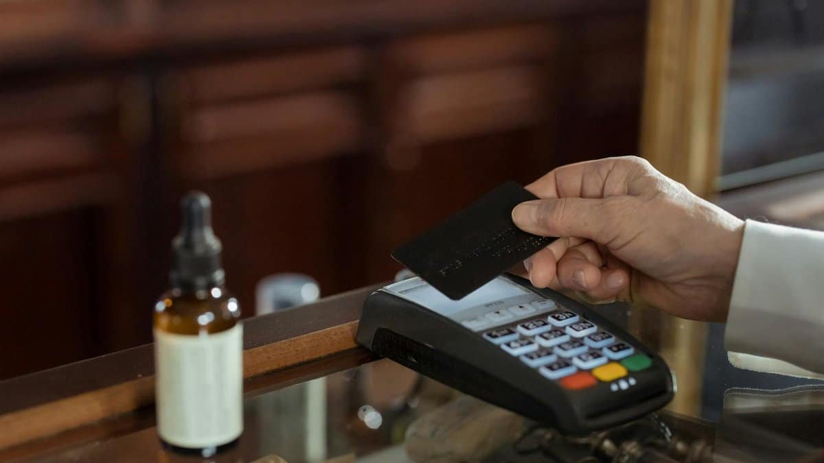 A close-up shot of a hand using a credit card with a swipe machine for payment.