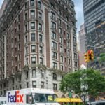 FedEx truck on a bustling street in New York City with skyscrapers and traffic, showcasing urban life.