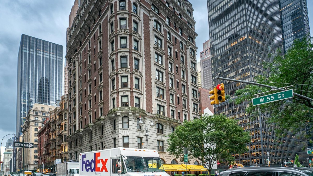 FedEx truck on a bustling street in New York City with skyscrapers and traffic, showcasing urban life.