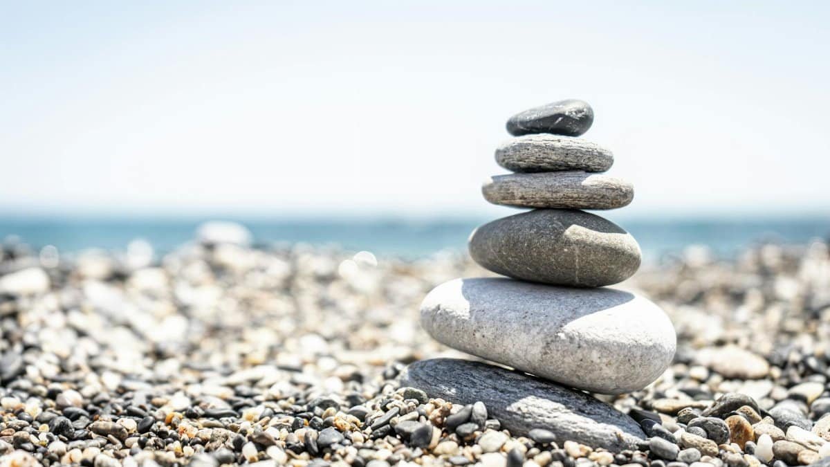 Peaceful stacked stones on a sunny pebble beach, symbolizing balance and tranquility.