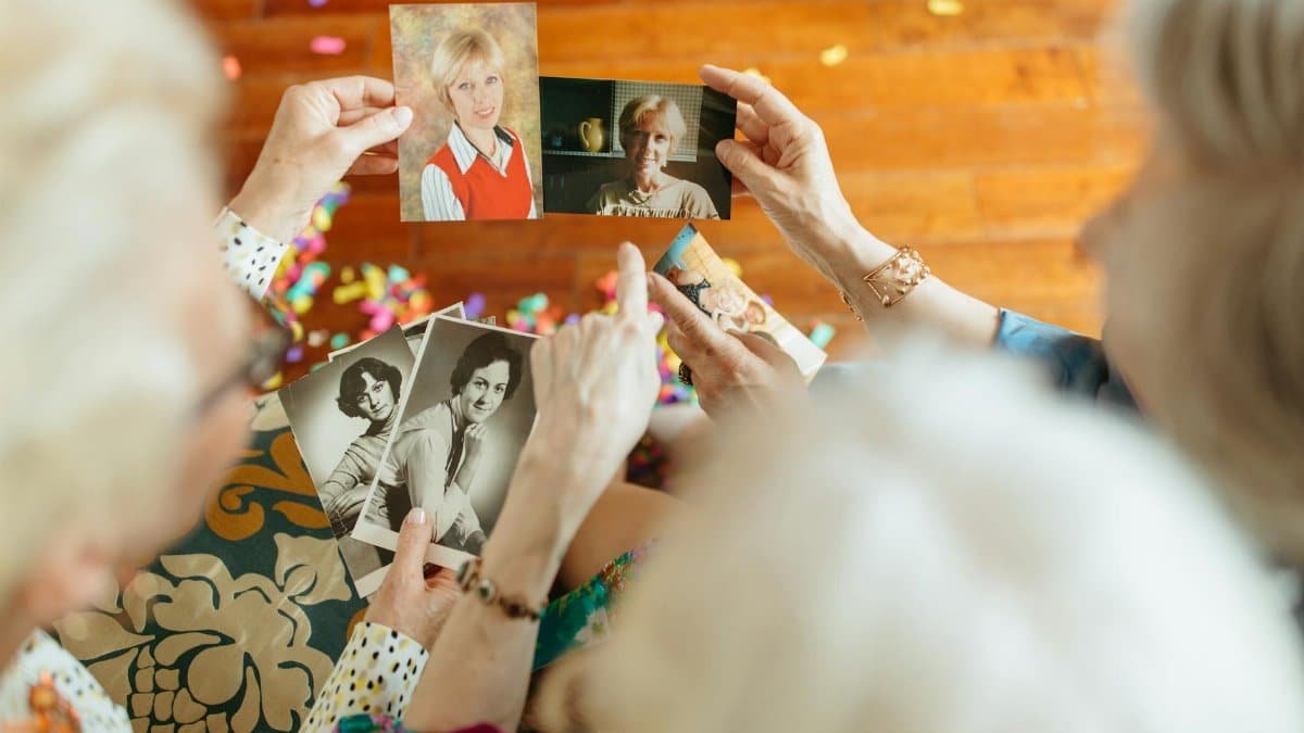 Elderly women nostalgically view vintage photos, reflecting on past memories.