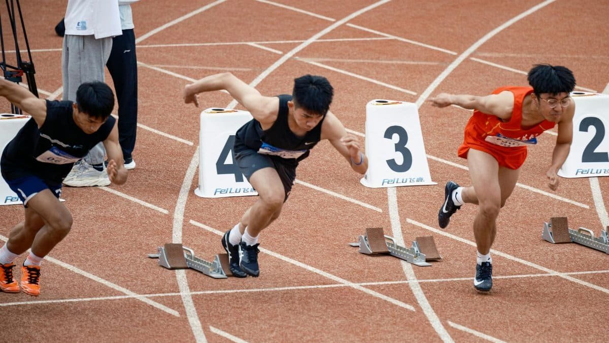 Young male sprinters launching off at the starting line, showcasing athletic determination on the track.