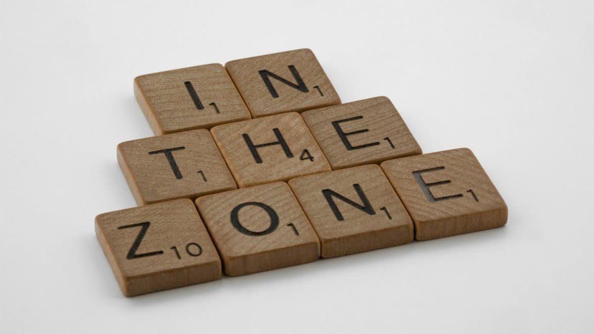 Scrabble tiles spelling out 'In the Zone' on a clean white background, symbolizing focus and concentration.