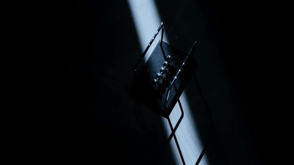 Newton's cradle in a dark room with striking light, showcasing physics concepts.