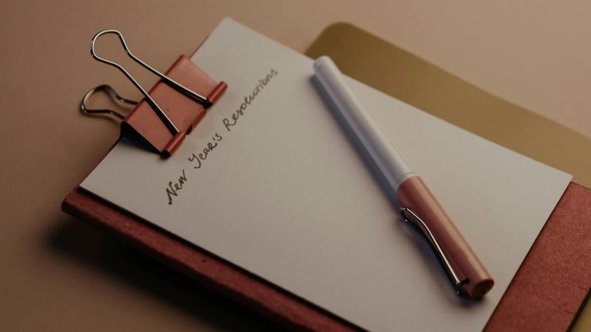 A stylish New Year's resolution planner with pen and paper clip on desk.