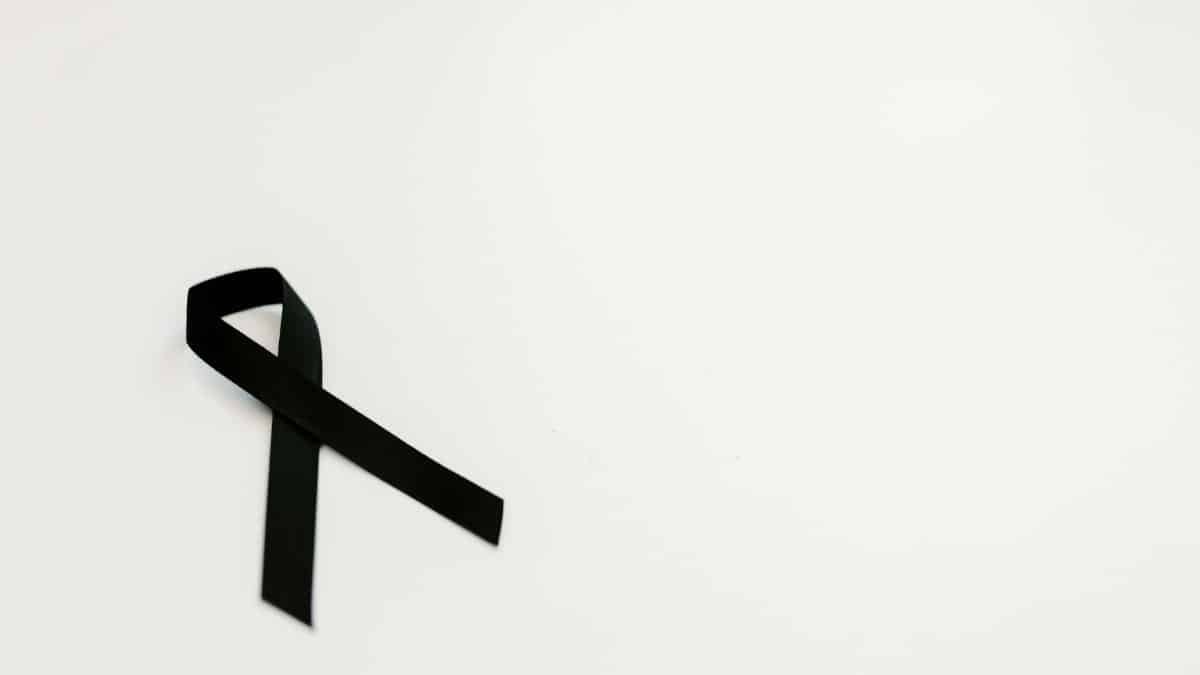 A black ribbon on a white background symbolizing mourning and remembrance, with ample copy space.