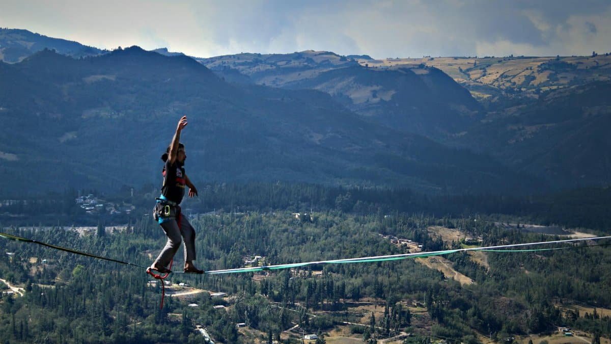 A person walking on a slackline against stunning Sutatausa mountains in Colombia.