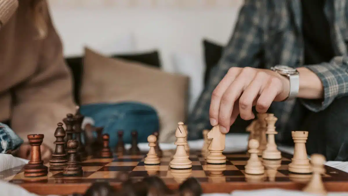 Two people play an intense chess game indoors, focusing intently on strategy.