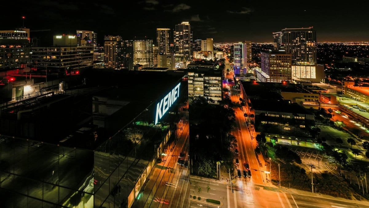 Drone view of asphalt roads between illuminated multistory buildings at night in Fort Lauderdale city