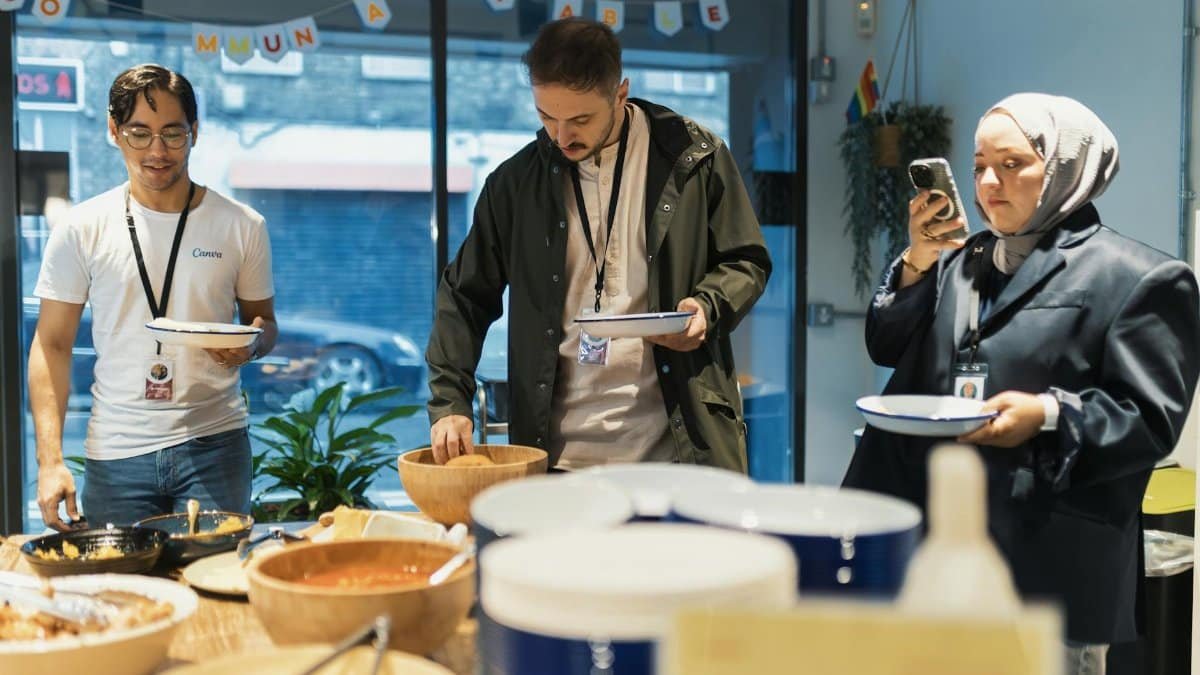 A diverse group of adults enjoying a casual buffet indoors with plates and food prepared for serving.