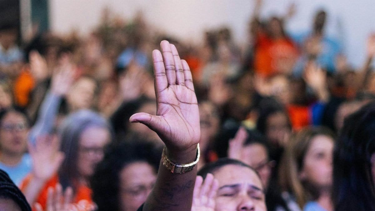 A diverse group raising hands in devotion, capturing unity and community spirit in a lively setting.