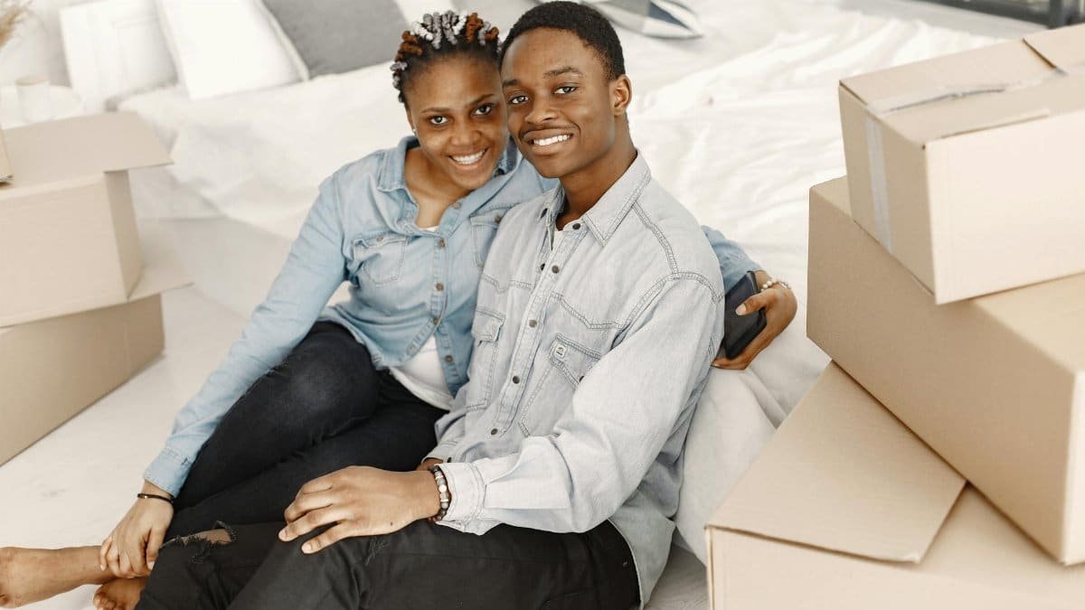 Cheerful couple sitting among boxes, enjoying their new home together.