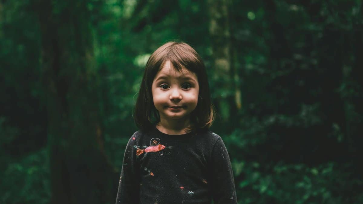 Cute child standing amidst a dense, green forest, exuding innocence and wonder.