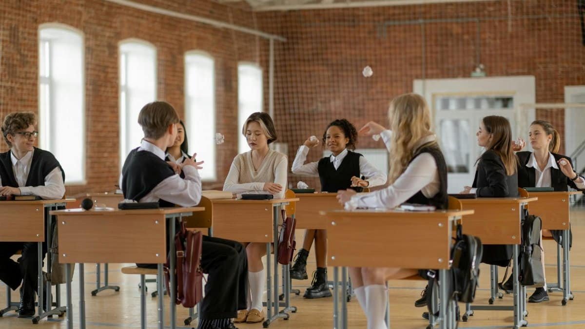 A diverse group of students wearing uniforms interacting in a classroom, emphasizing school life and education.