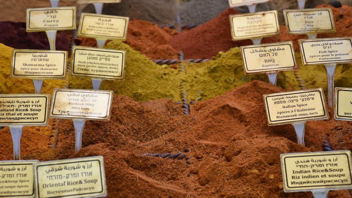 From above of pile of different dry spices for rice and soups with inscriptions on papers in local bazaar