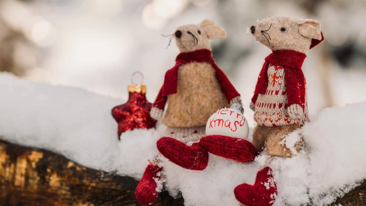 Adorable felt mice with Christmas decorations on snow create a warm holiday atmosphere.