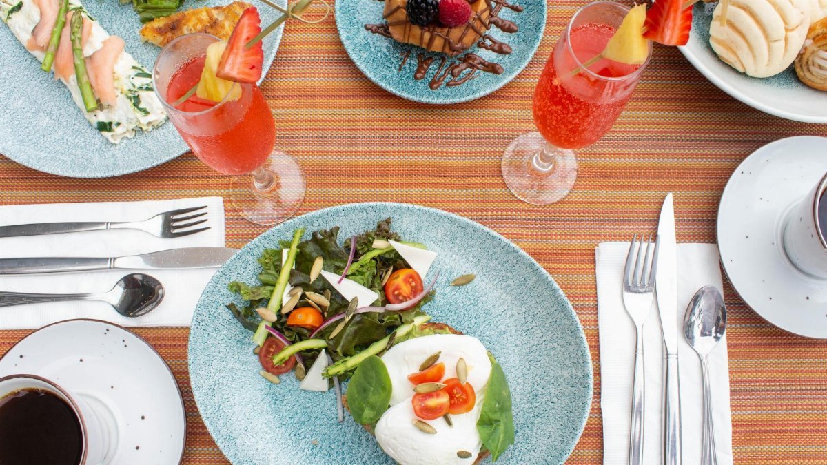 A vibrant breakfast table setting in Puerto Vallarta with fresh salad, pastries, and drinks.