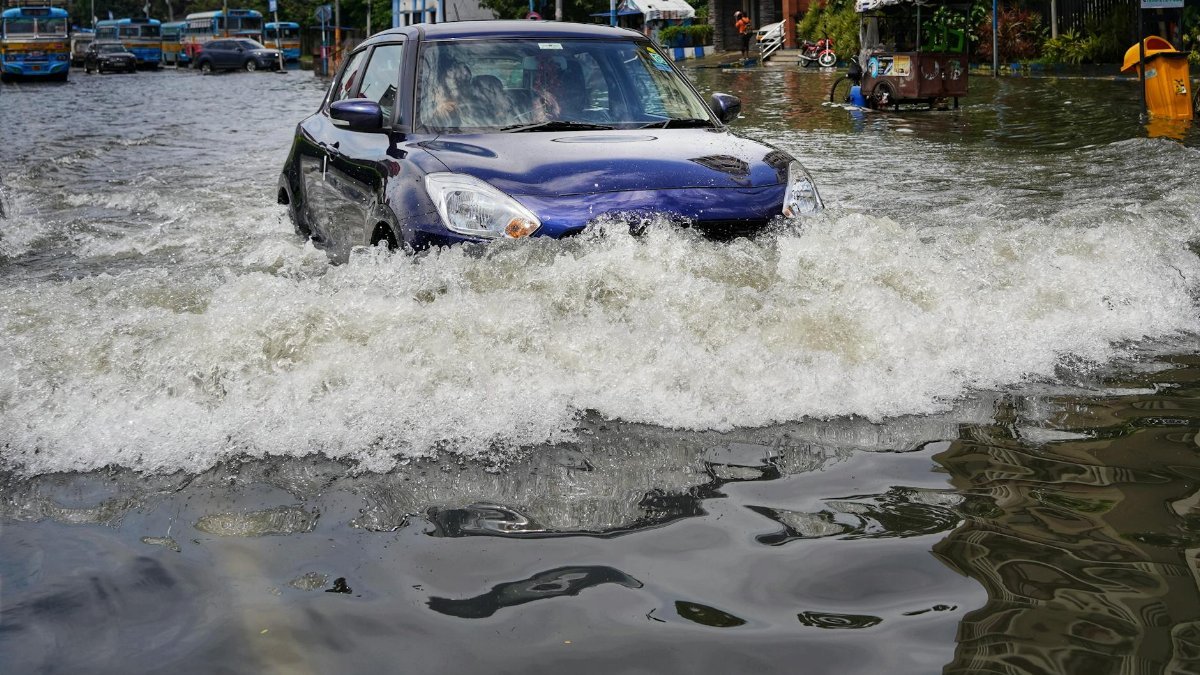 A blue car drives through flooded streets in Kolkata, India after heavy rain.