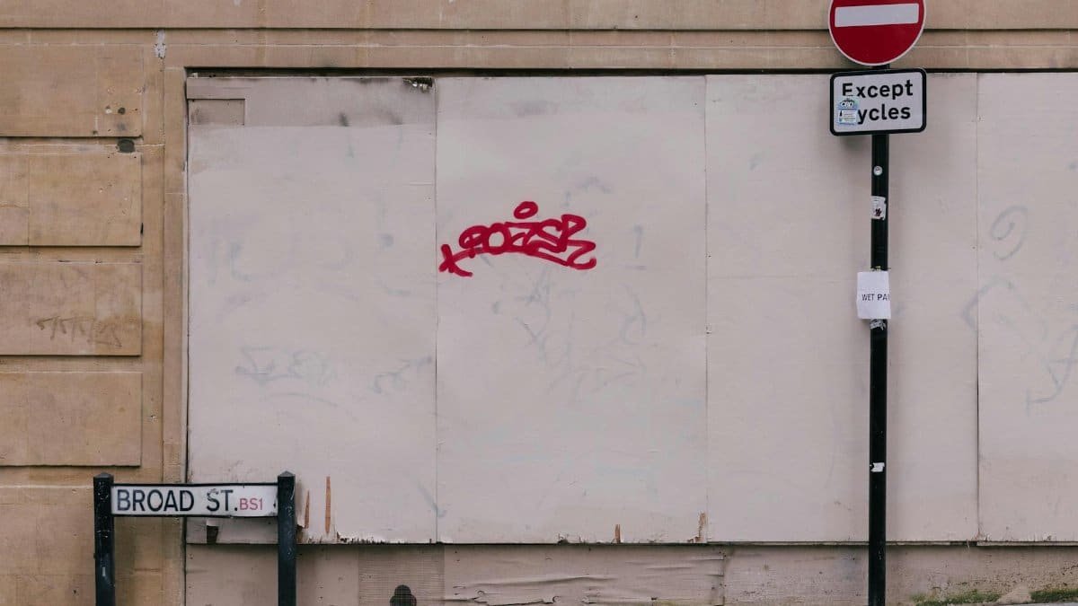 Street view featuring a no entry sign, graffiti, and signs on a city wall.