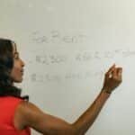 Professional woman writing real estate prices on a whiteboard for rental properties.