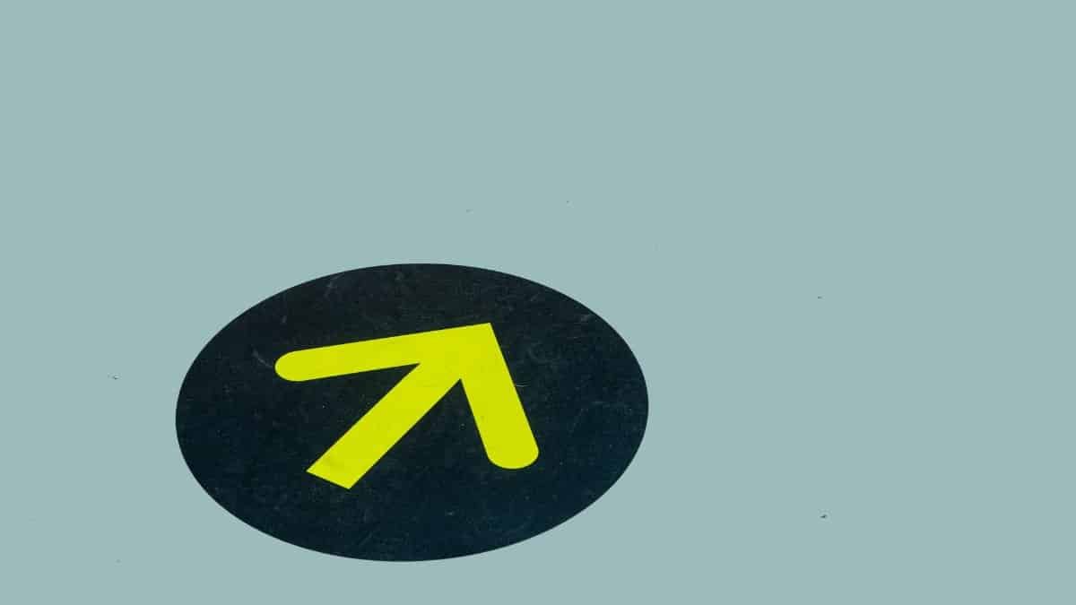 Minimalist image of a yellow arrow on a blue floor indicating direction, ideal for navigation themes.