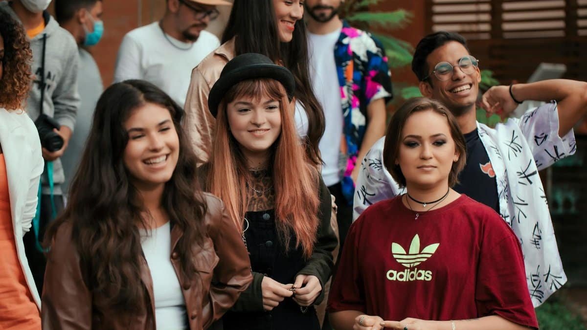 A lively group of young adults enjoying a casual outdoor gathering, smiling and socializing.
