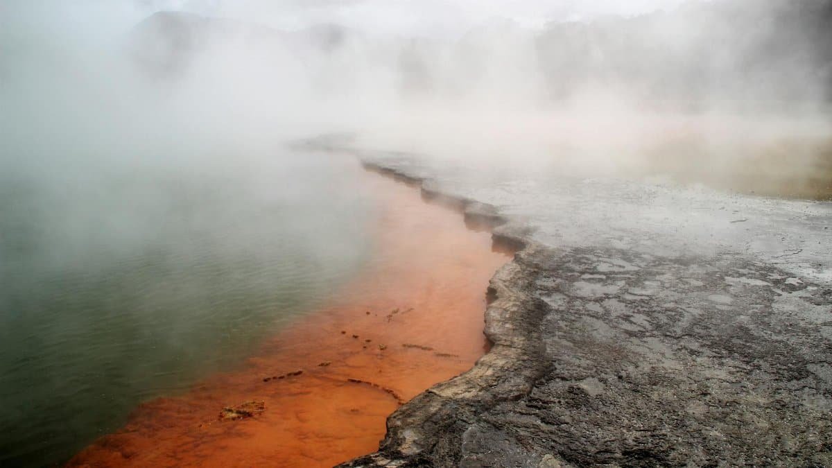 Dramatic view of a steaming geothermal spring with vibrant colors in Rotorua, New Zealand.