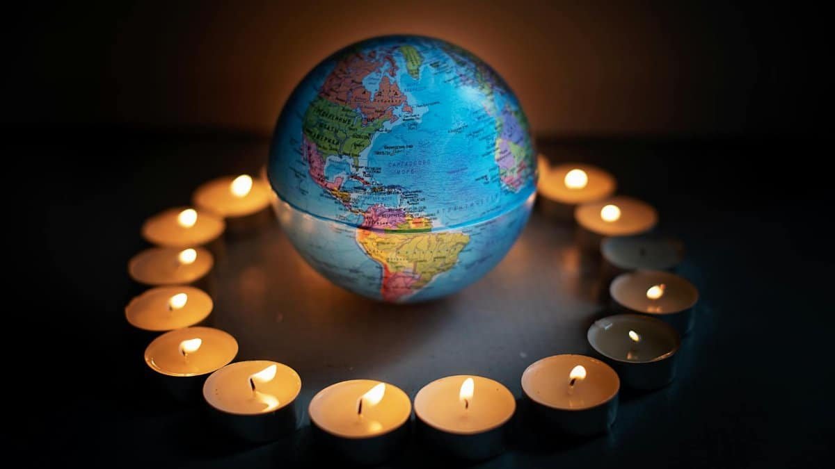 A globe encircled by candlelights symbolizing global unity and peace.