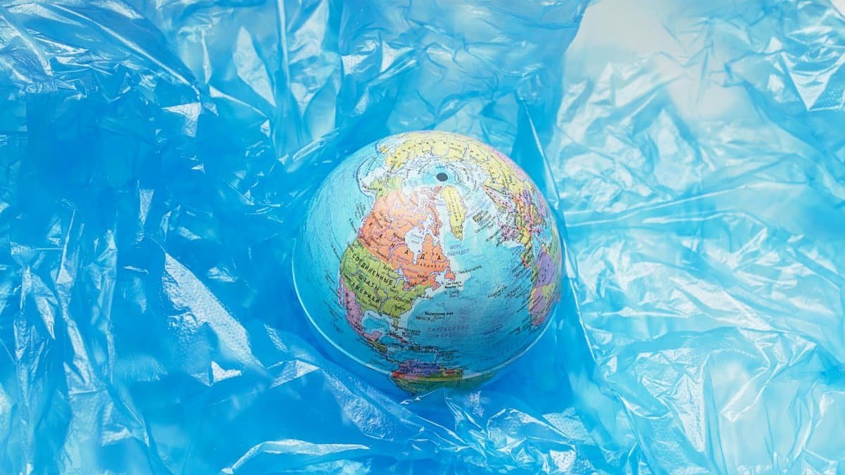 A globe wrapped in blue plastic, symbolizing global pollution and environmental issues.