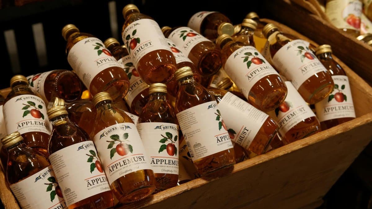 A variety of bottled apple juice arranged in a wooden crate, perfect for market displays.