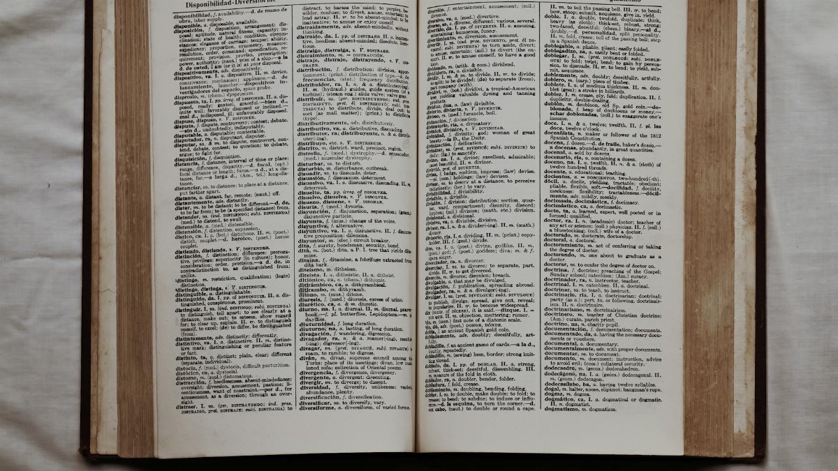 Close-up of an open dictionary showing English and Spanish translations, flat lay view.