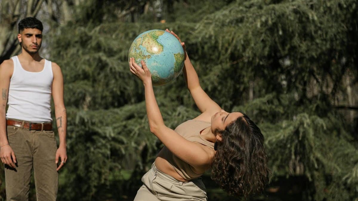 Two adults outdoors holding a globe, embracing global concepts and unity.