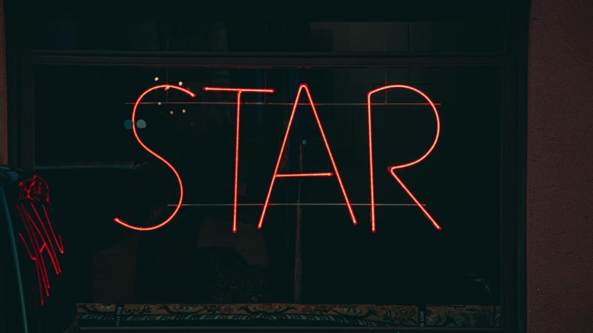 Vibrant neon 'STAR' sign illuminating a Berlin storefront at night. Urban street vibe.