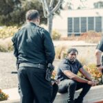 Law enforcement officers interacting with a person outdoors, displaying cooperation and safety enforcement.