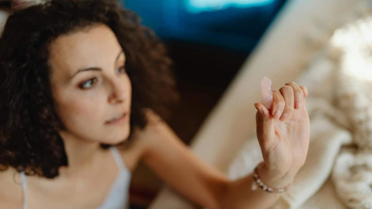 Focused woman holding a healing crystal indoors, embodying relaxation and alternative medicine.