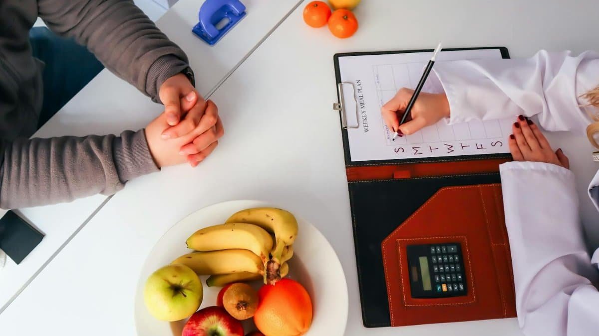 Top view of a dietitian planning a healthy diet with fresh fruits on the table, focusing on health and nutrition.