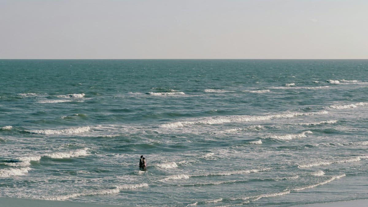 A picturesque scene of a couple enjoying the waves at Galveston beach, Texas.