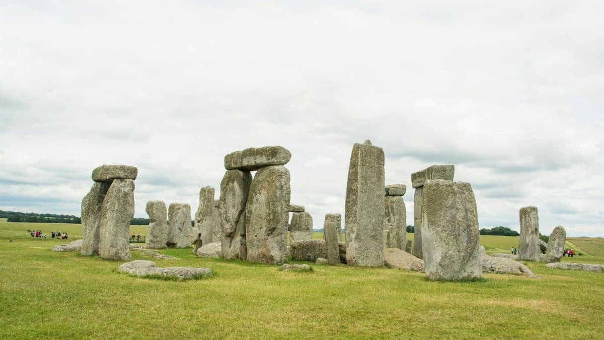 View of Stonehenge against a cloudy sky with green grass surroundings.