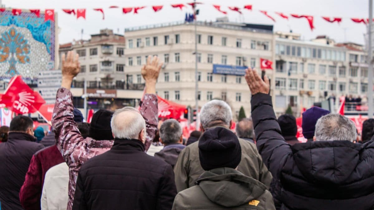 Crowd at a public rally with flags raised, focusing on community spirit and engagement.