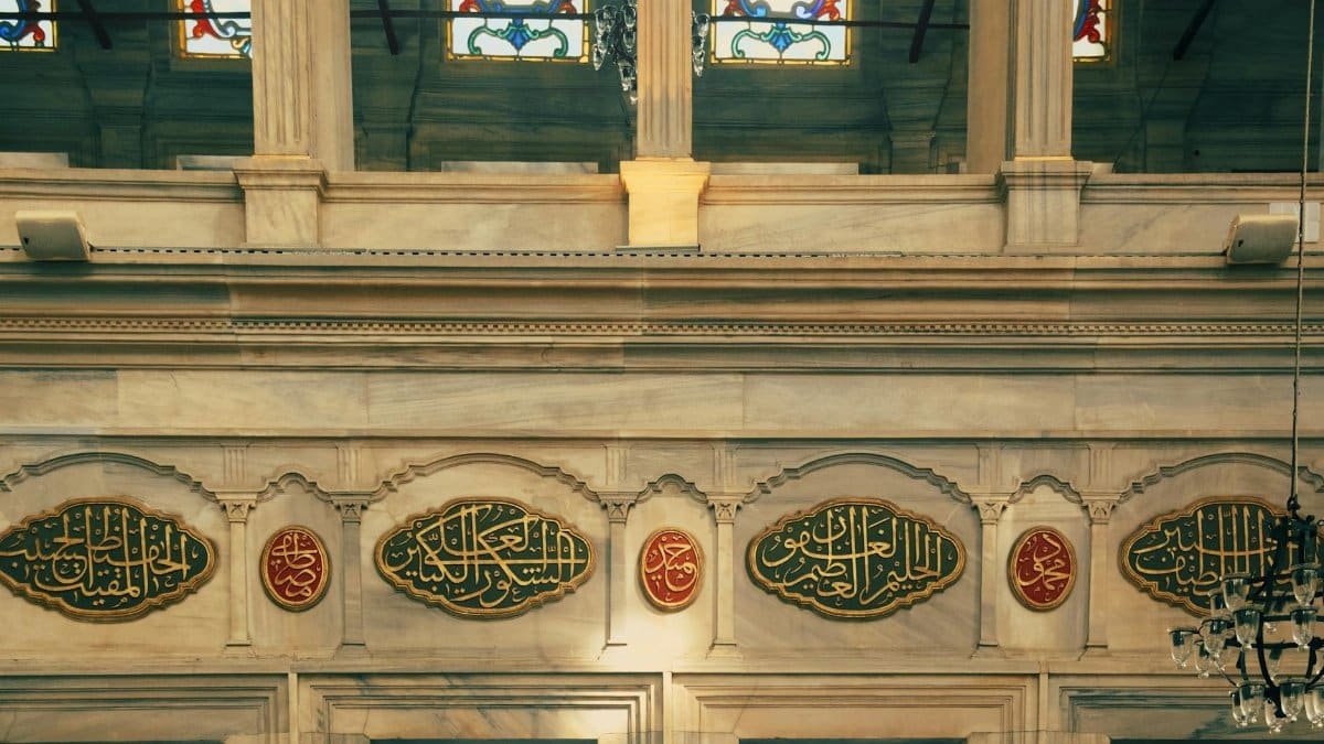 A detailed view of Islamic calligraphy and stained glass in a historic mosque interior, showcasing architectural elegance.