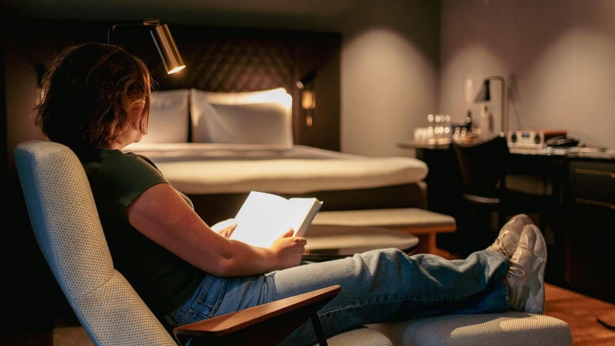 Woman relaxing and reading in a modern Stockholm hotel room, creating cozy ambiance.