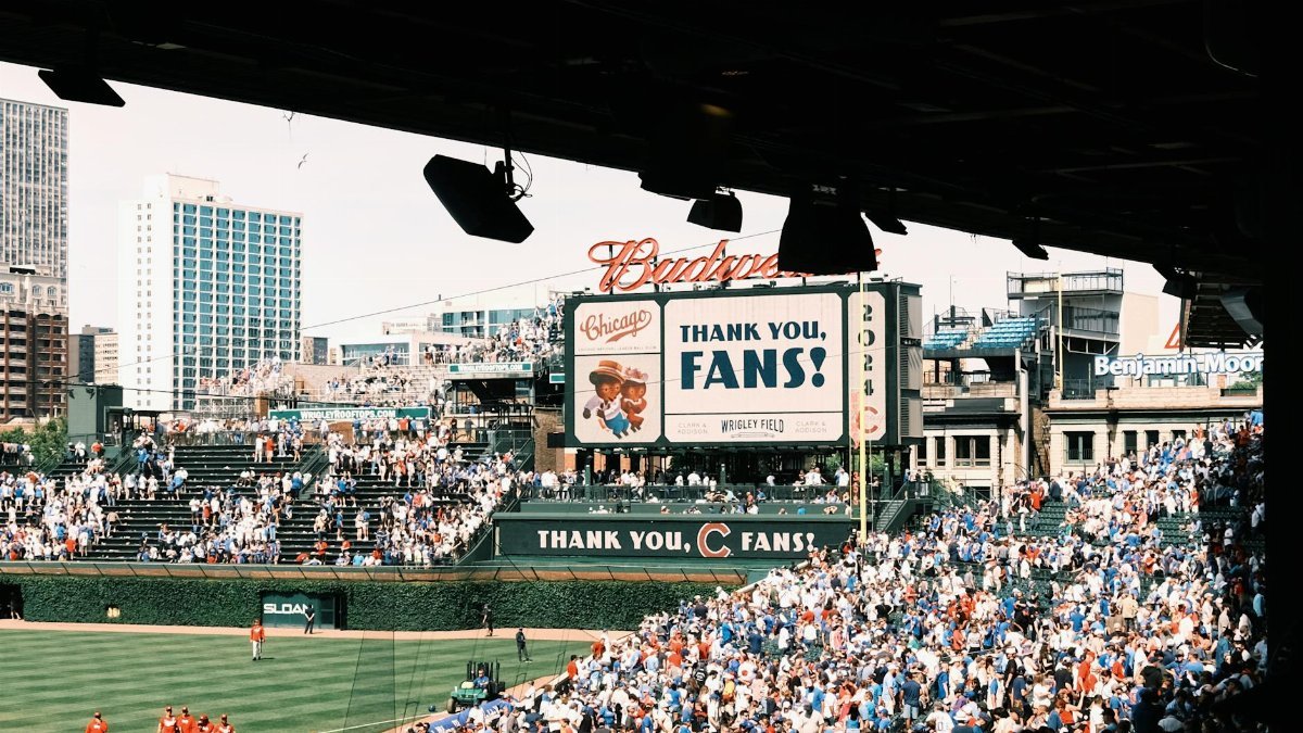 Crowd enjoying a baseball game at Wrigley Field, Chicago's iconic stadium, on a sunny day.