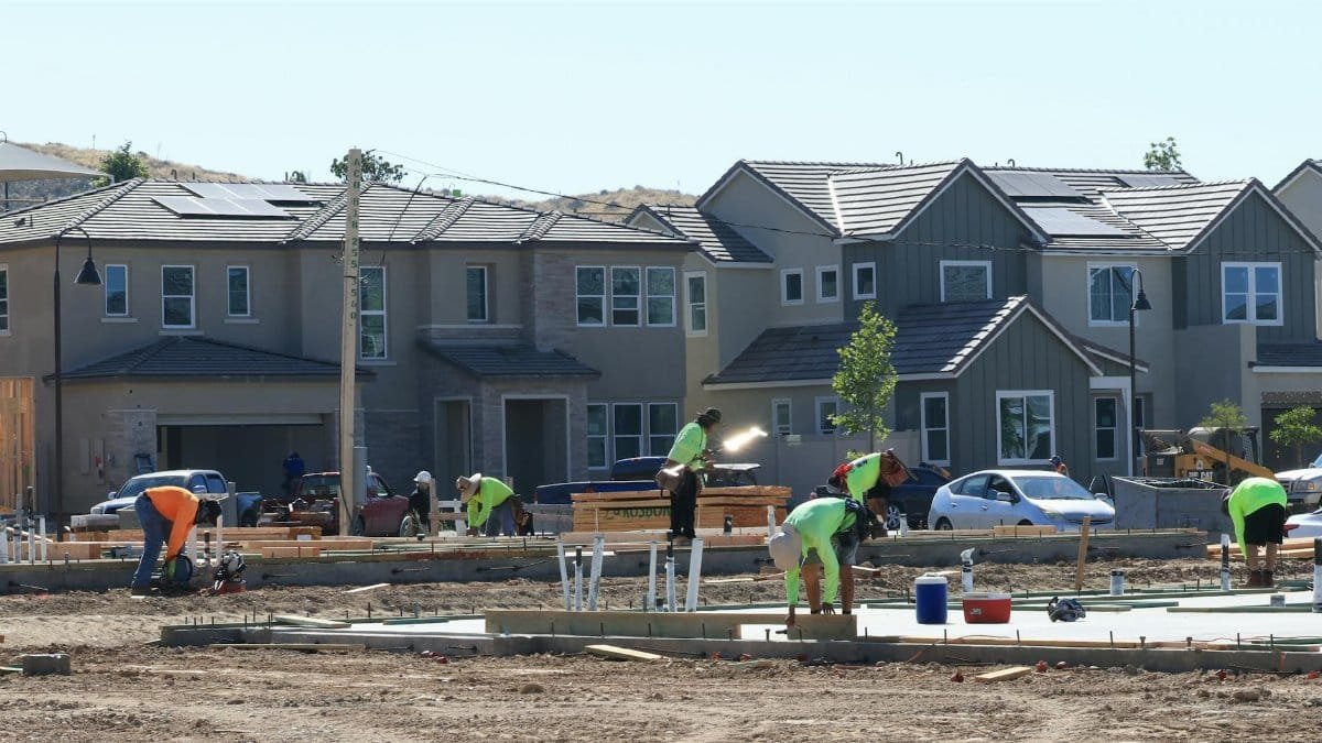 Construction workers laying foundations in a modern housing development.