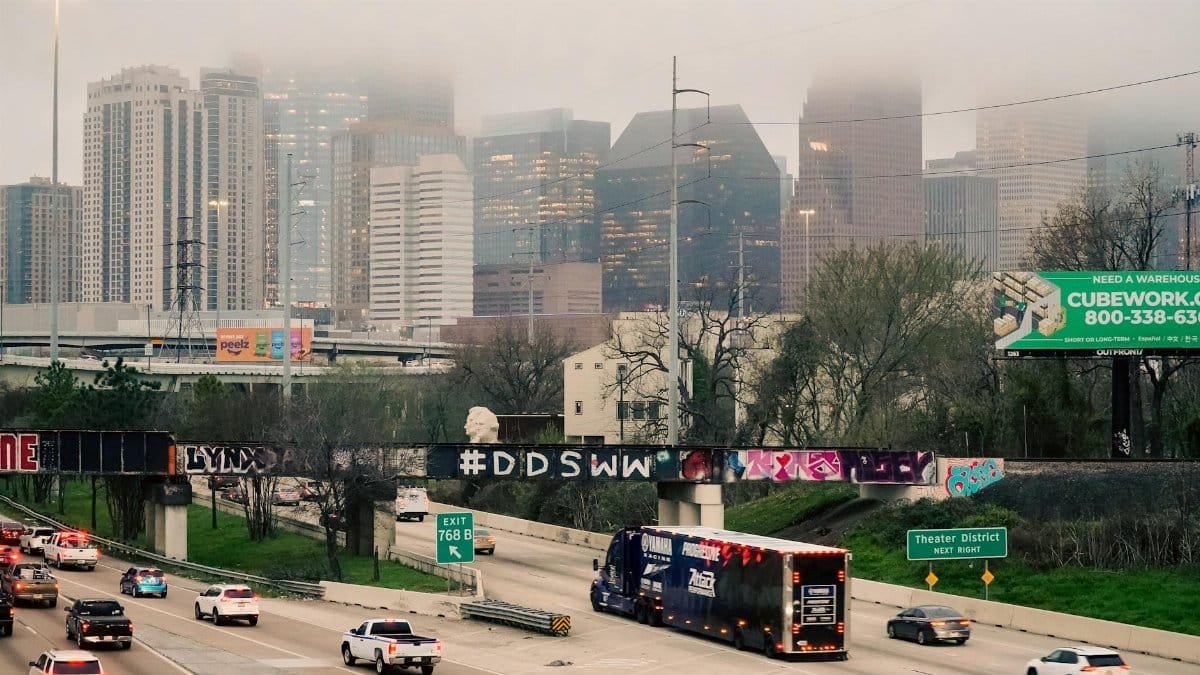 Commuters on a foggy morning with Houston skyline partially obscured by dense fog.
