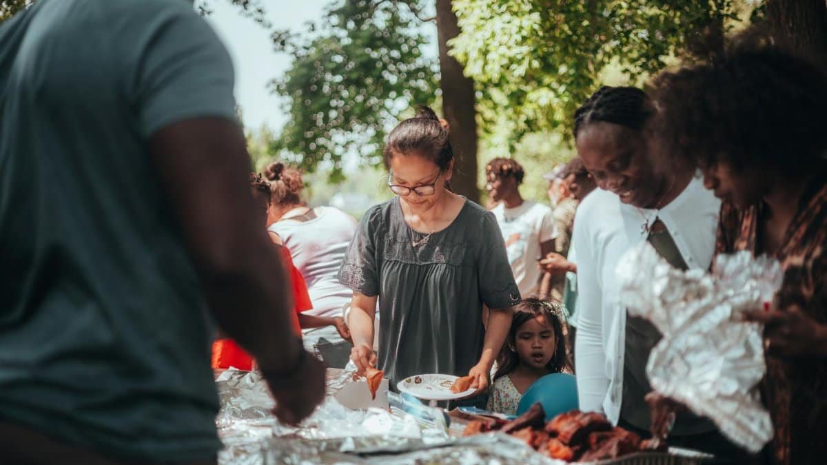 A lively barbecue gathering with diverse group outdoors enjoying food and summer weather.