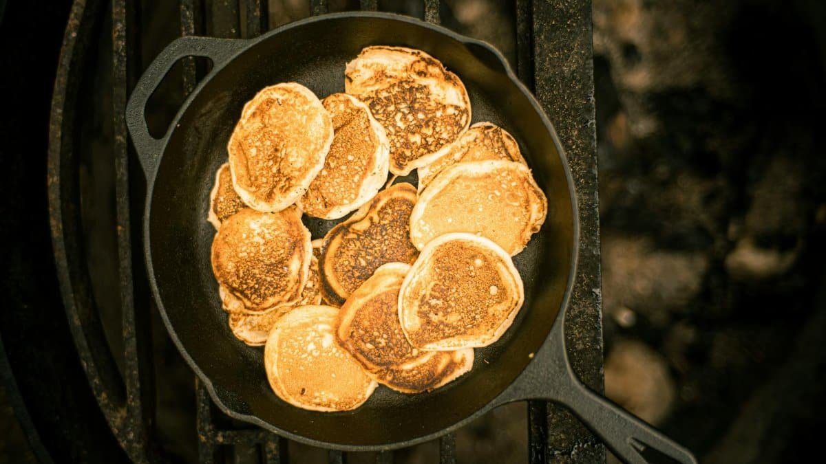 A delicious stack of golden pancakes cooked in a cast iron skillet, photographed from above.