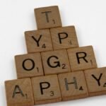 Close-up of wooden Scrabble tiles forming the word typography on a white background.