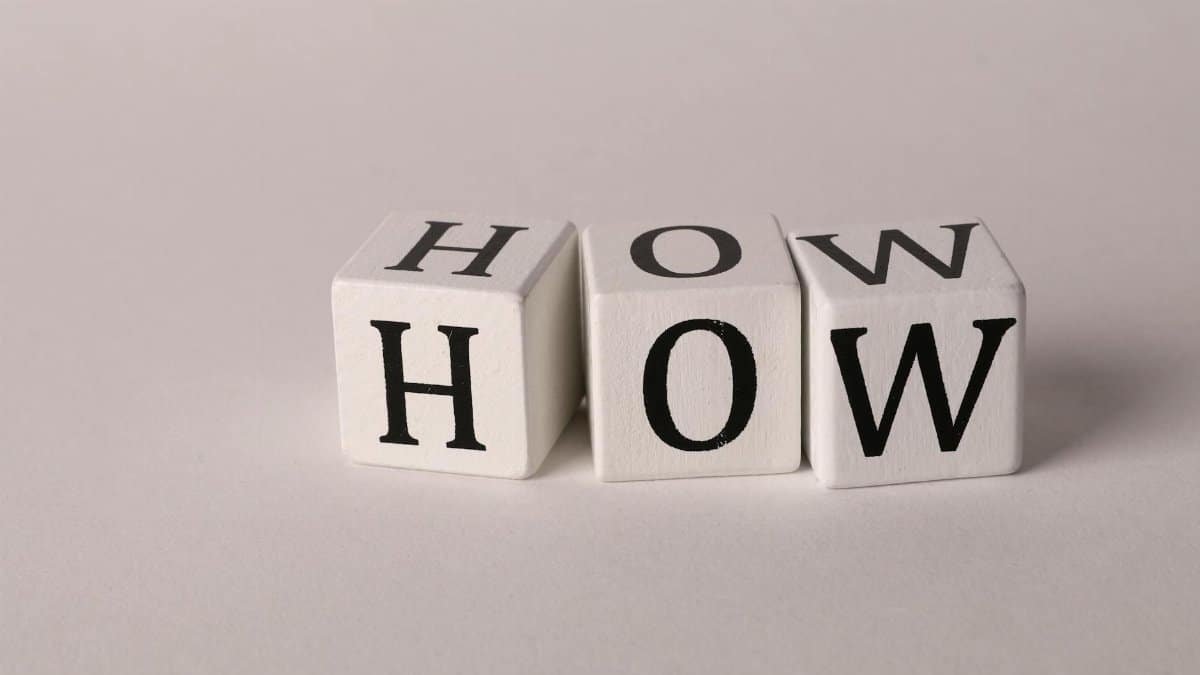 Close-up of white wooden cubes with the letters 'H', 'O', and 'W' arranged on a neutral background.