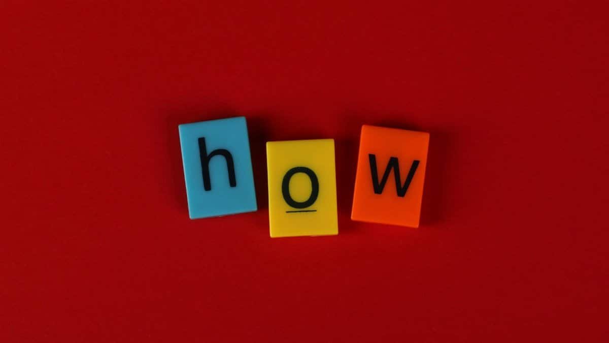 Colorful letter tiles spelling 'How' on a vibrant red background, ideal for educational content.